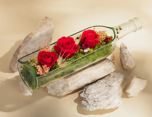 Composizione di rose stabilizzate in un vassoio bottiglia